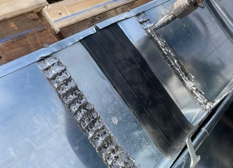 Soudure d'un élément de zinc au chalumeau sur un chantier