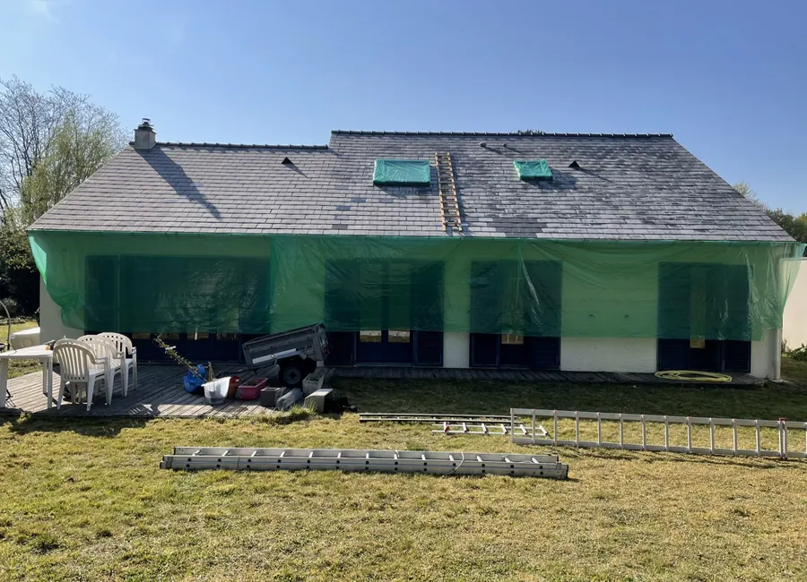 Chantier protégé par un filet, fenêtres de toit bâchées pendant les travaux