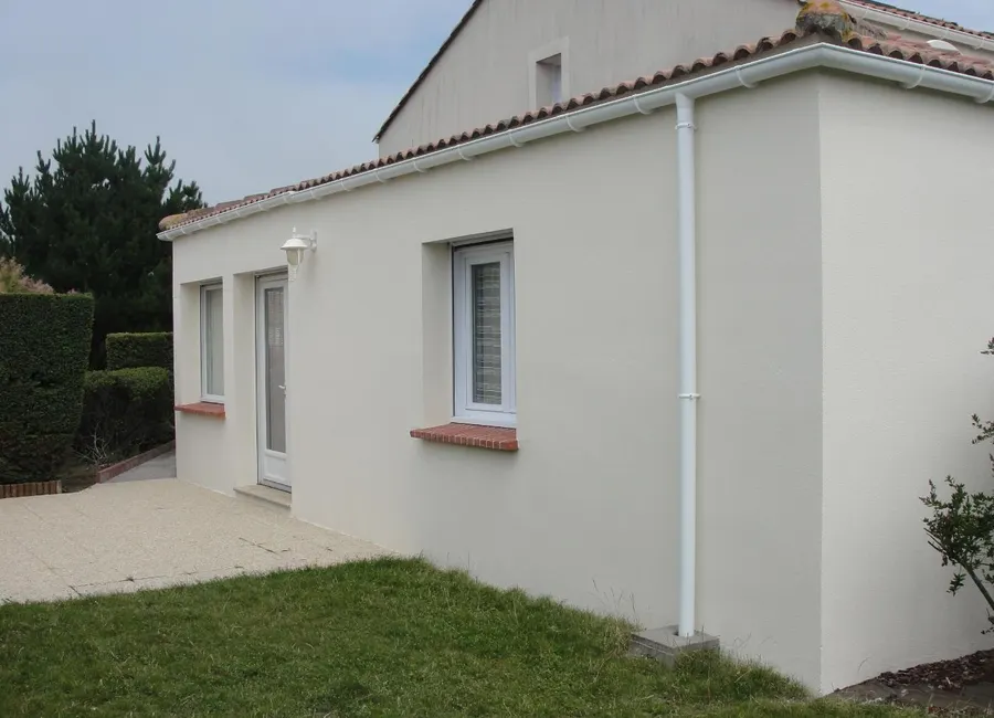 Façade en enduit crème refaite, avec descente de gouttière neuve